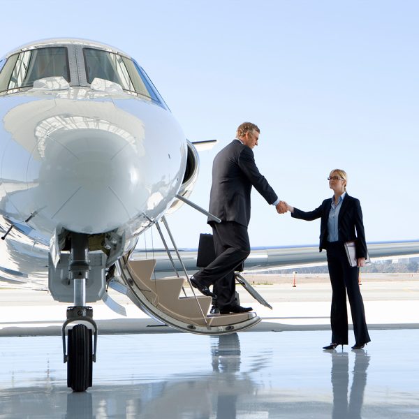 Businessman shaking hands with a businesswoman while getting out of the private jet.